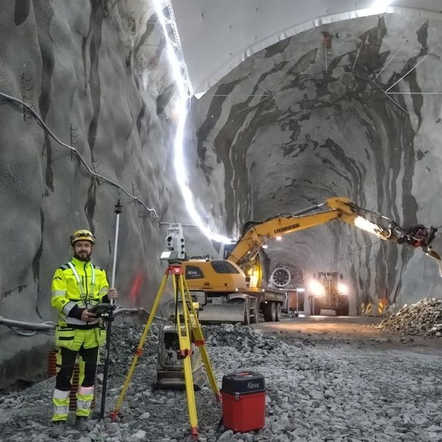 Betongarbeid i tunnel med gravemaskin og målingsutstyr